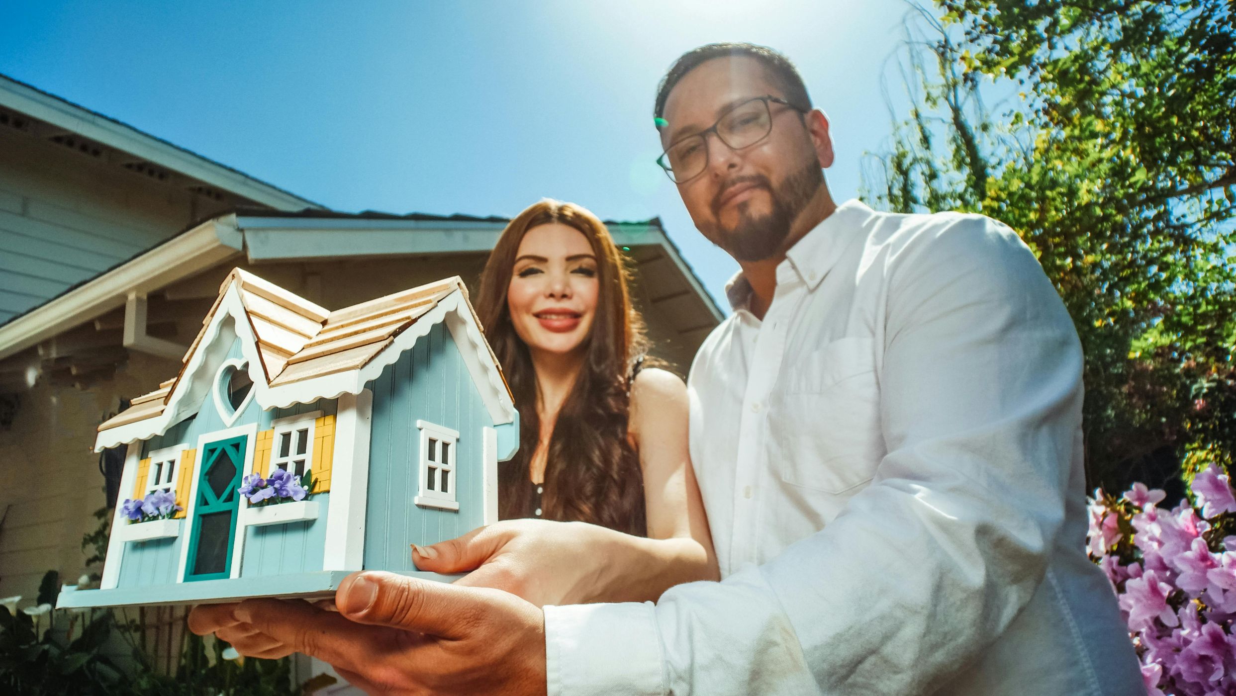 couple holding miniature house model: Melbourne brokers help next home buyers with home loans.