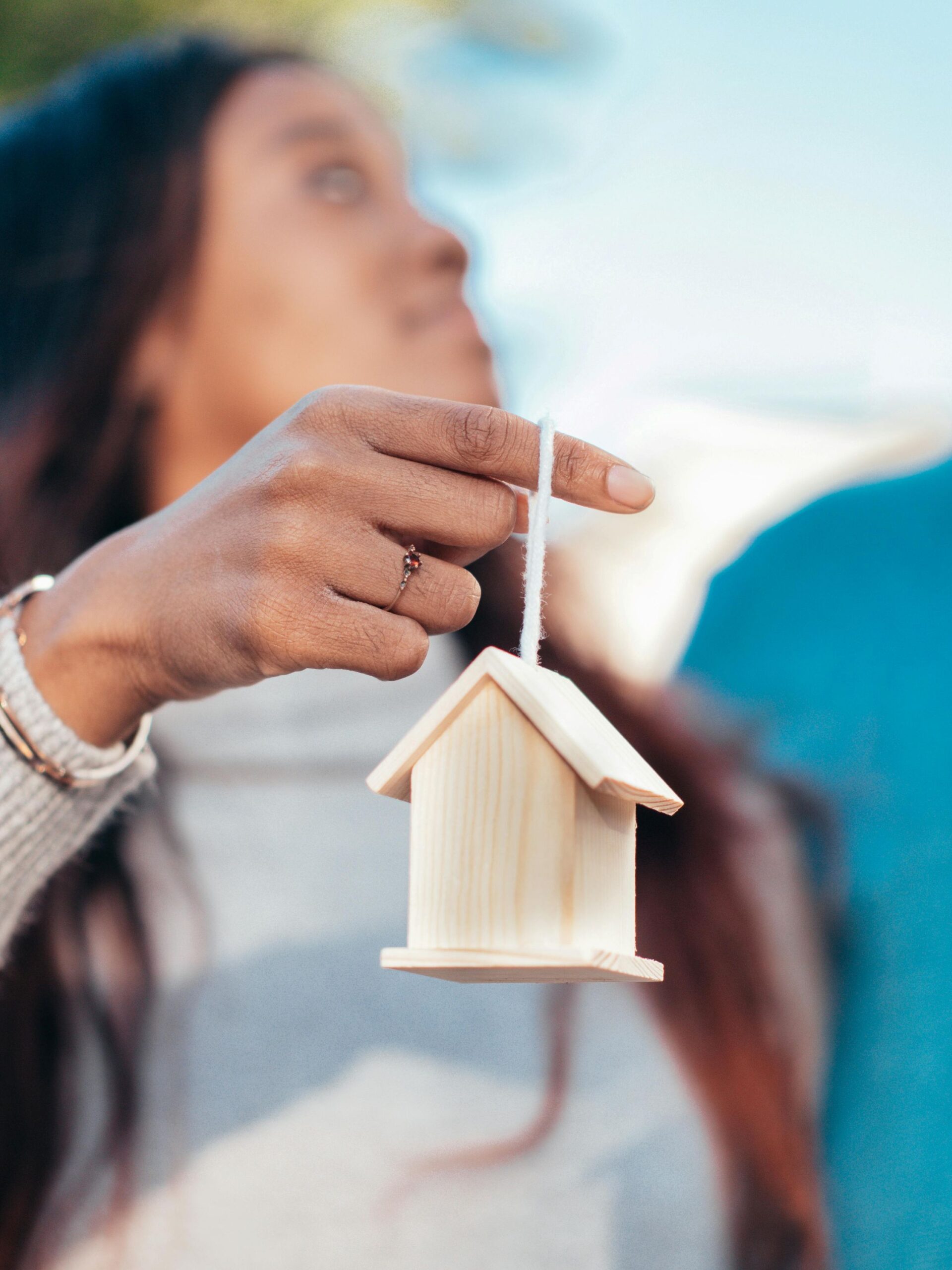 A female holding up a miniature house.
