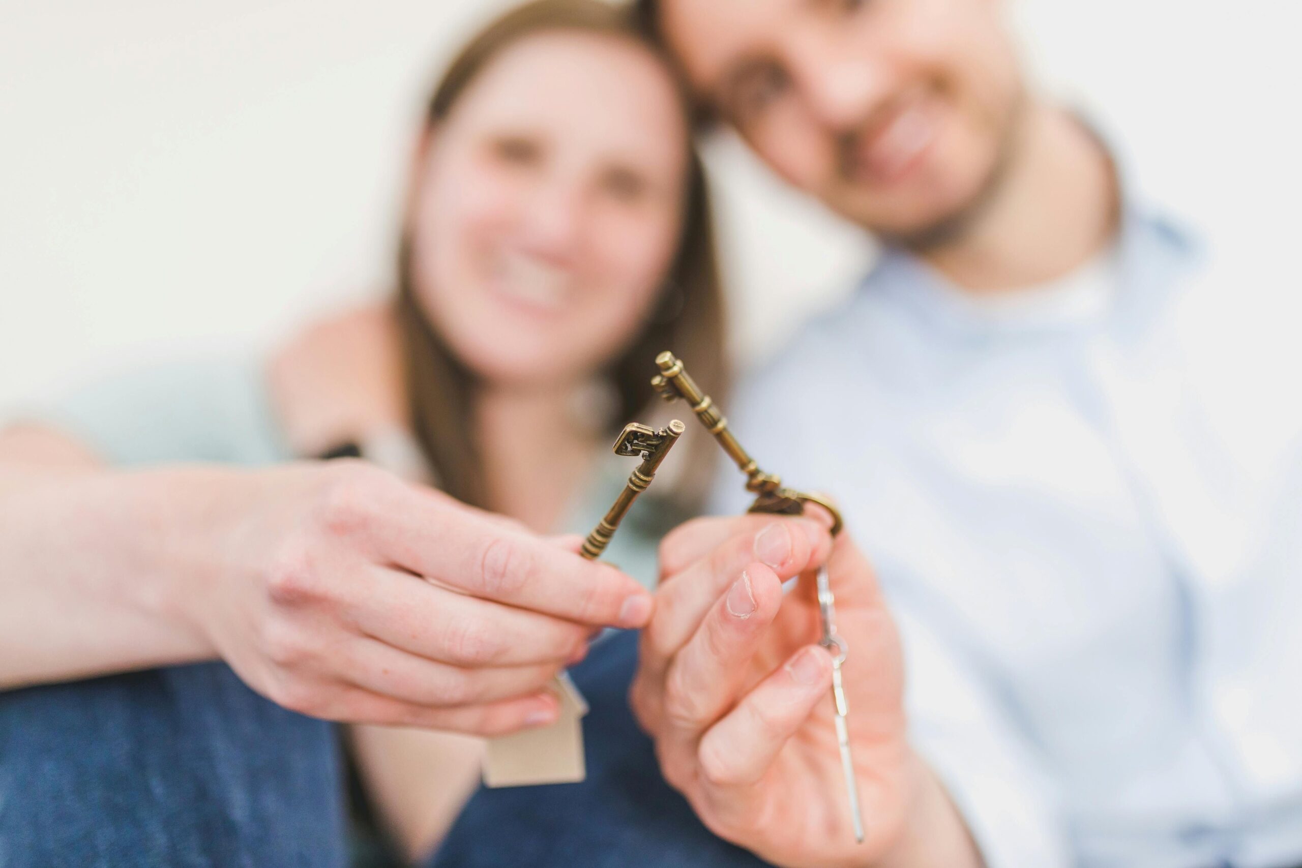 A sitting couple holding up a house key together.