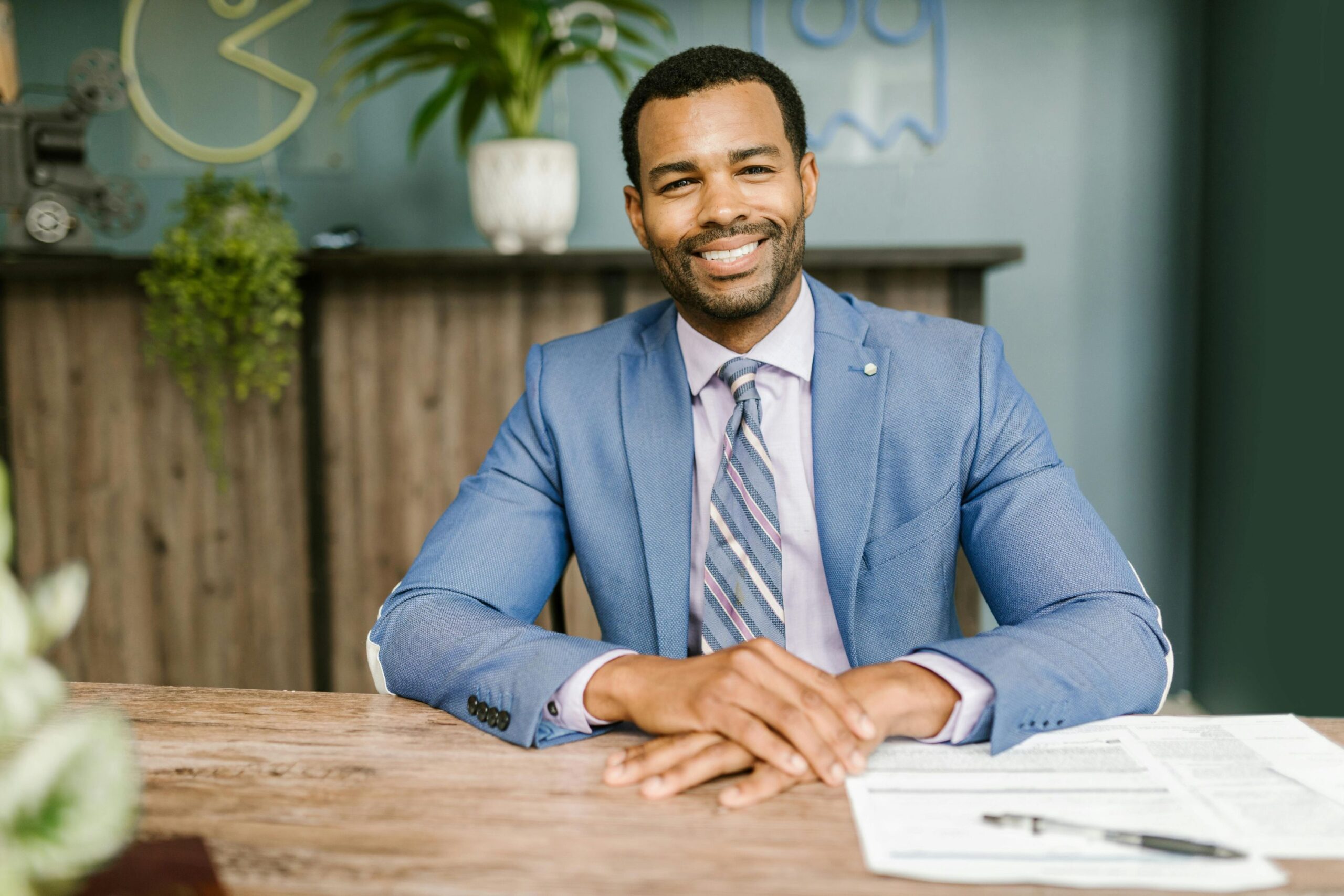 A smiling male mortgage broker seated on his desk.