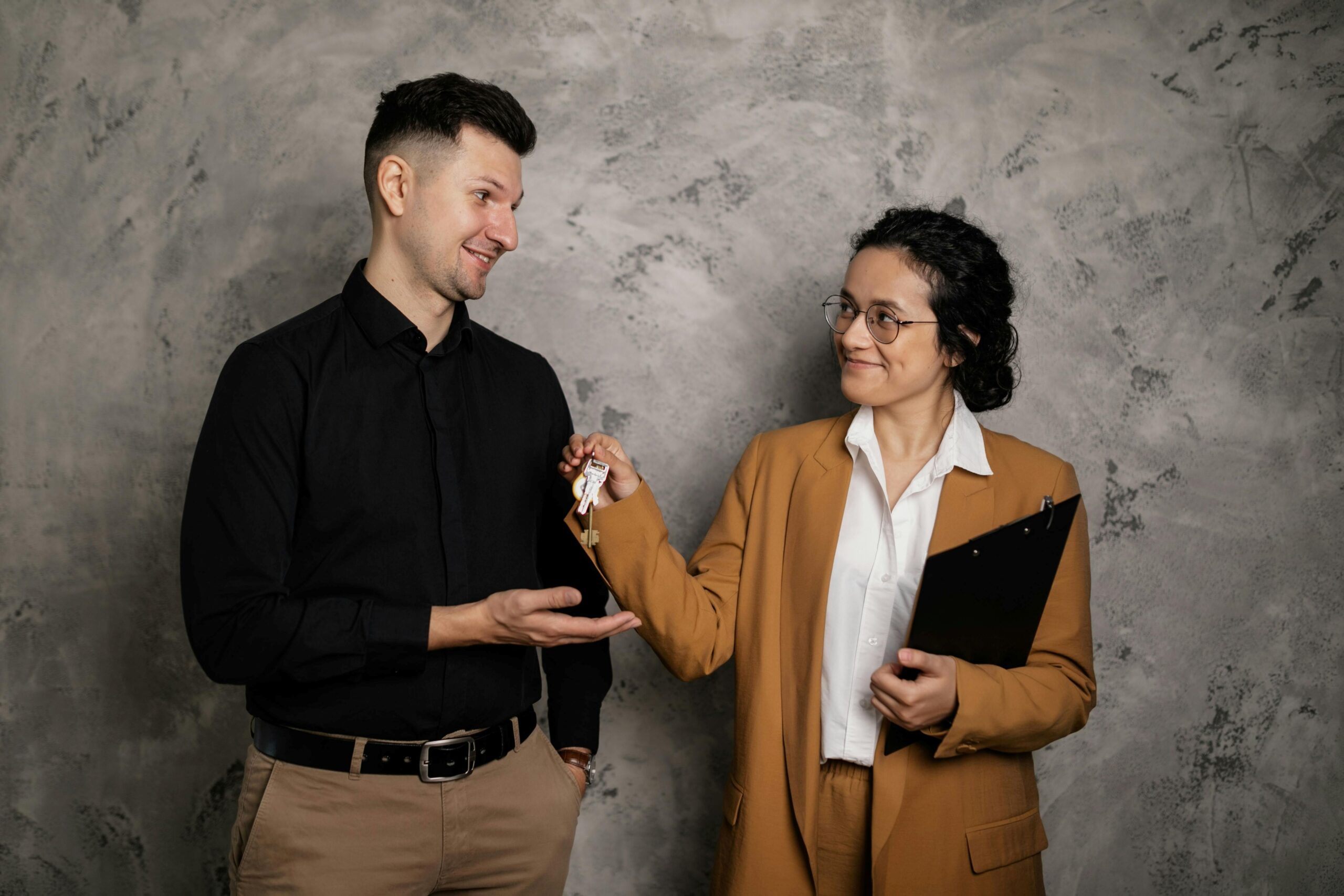 A female agent handing house key to a male client.
