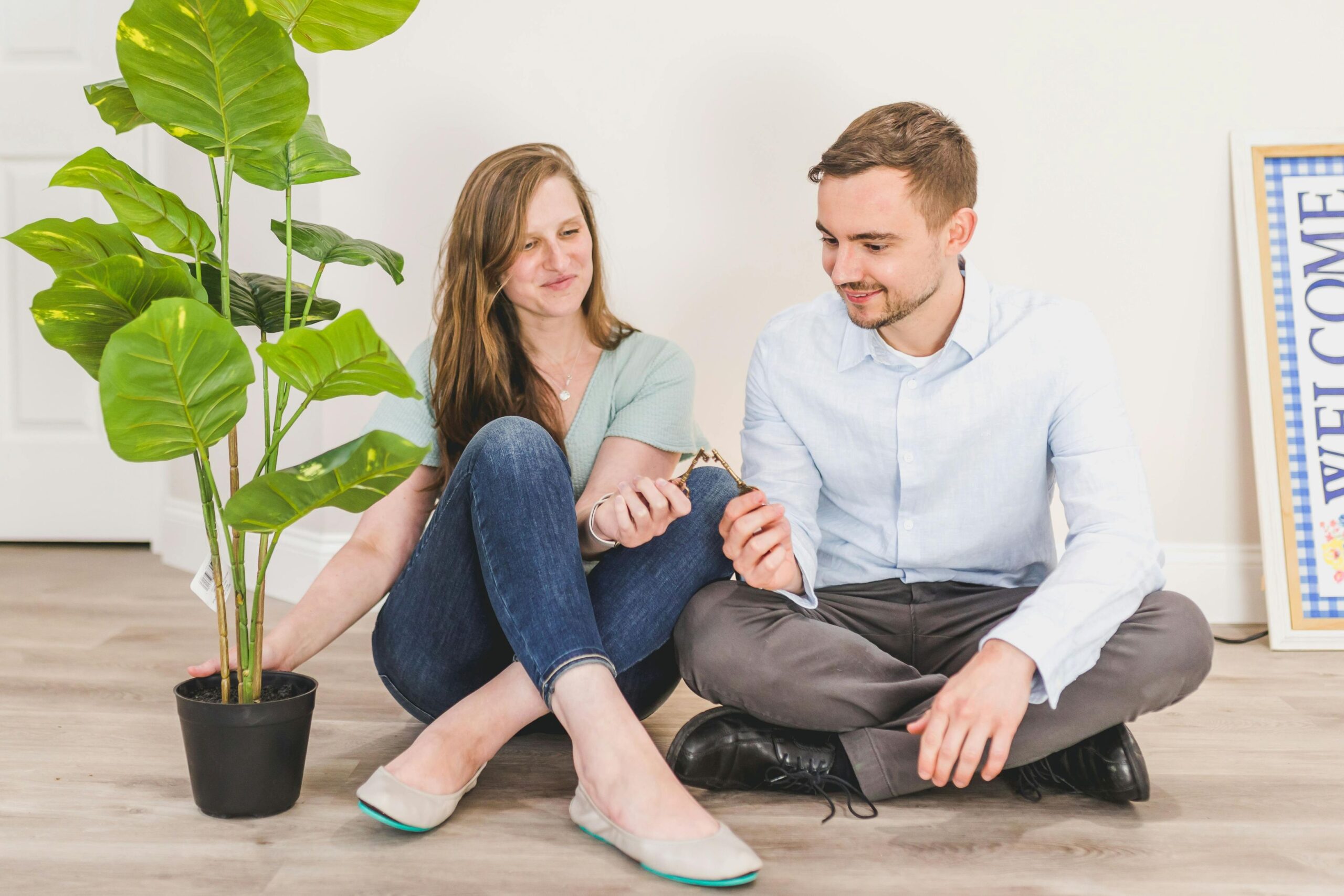 A couple sitting on the floor, holding up house keys.