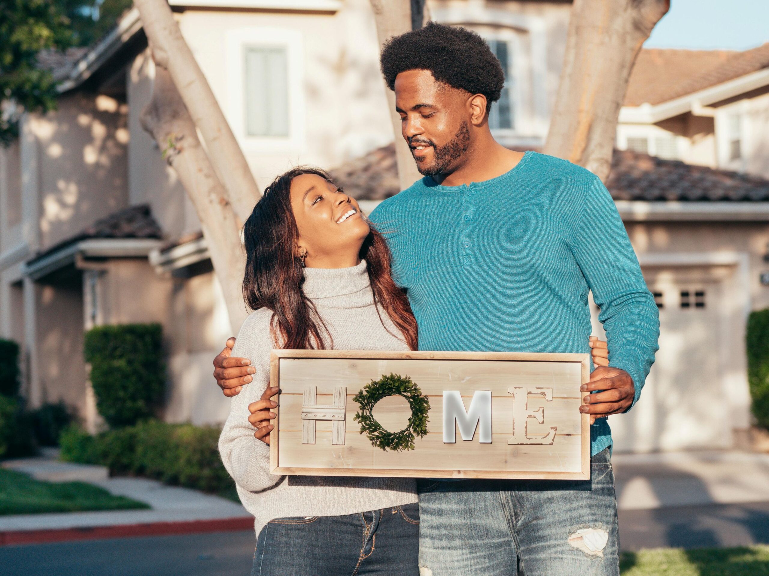 A couple holding up a sign that says home.
