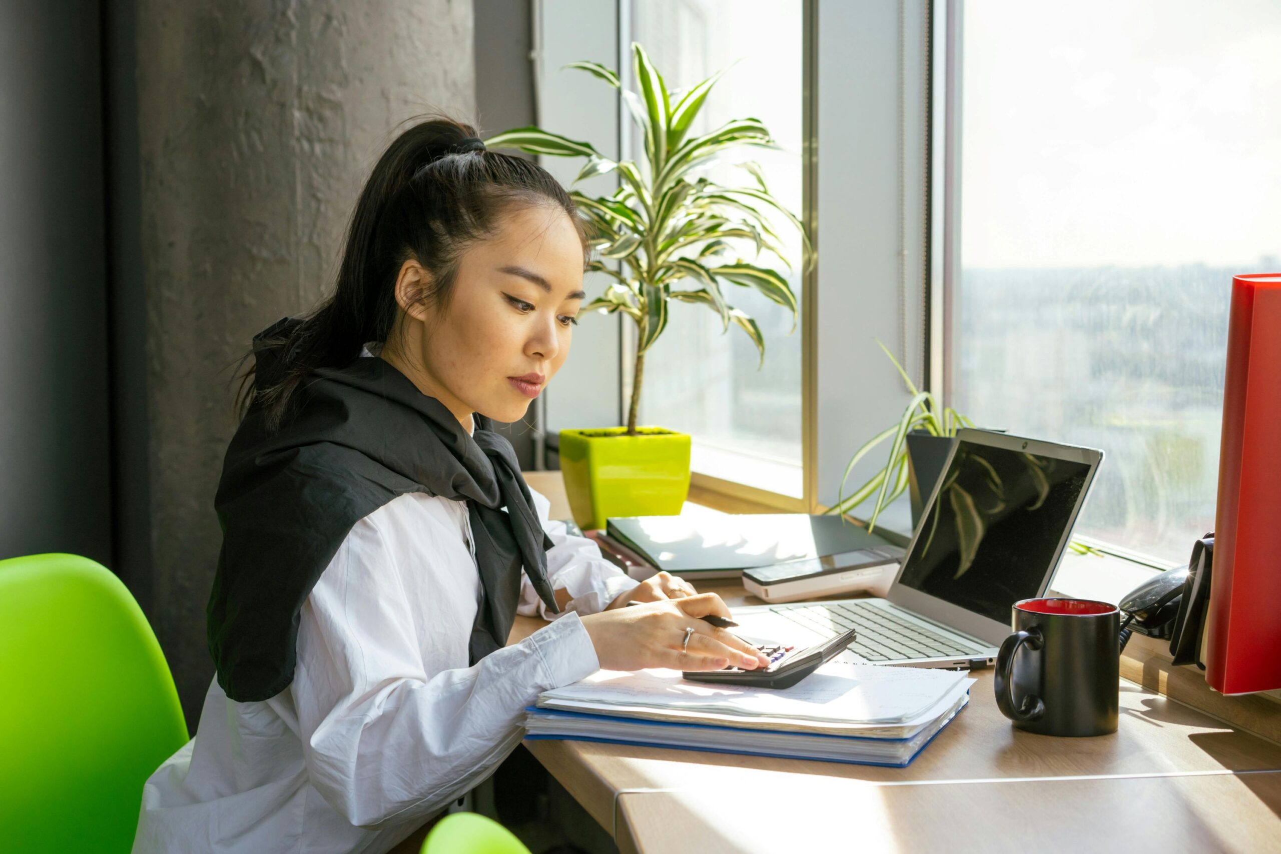 A female using a calculator while working on her desk.