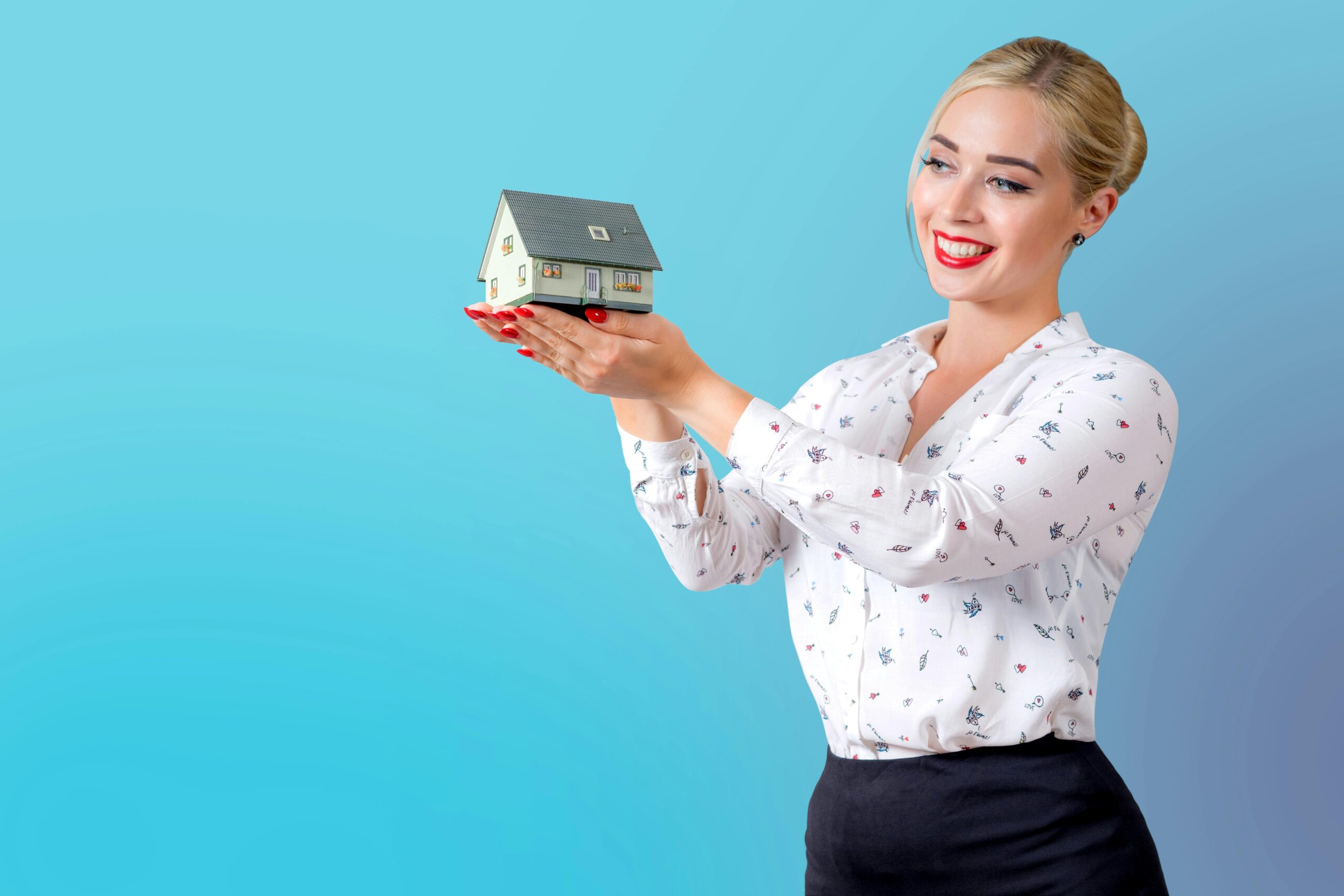 A female holding up a miniature house model.