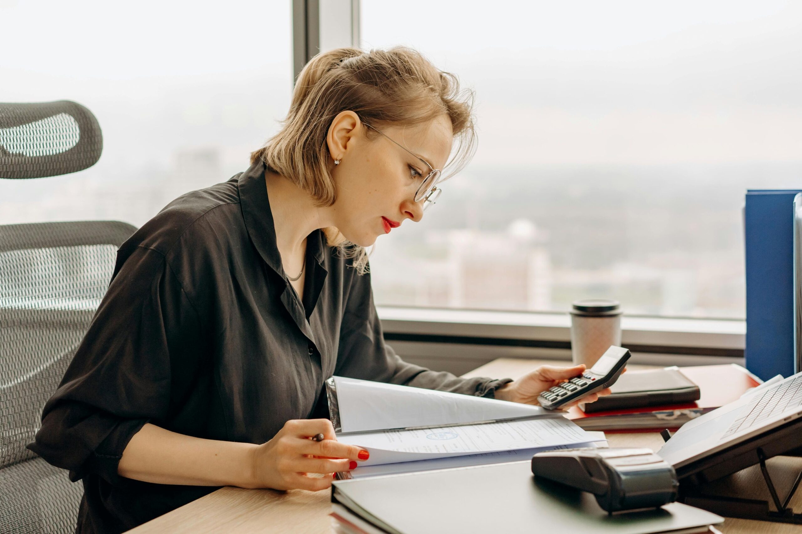 A woman in long-sleeves computing using a calculator.