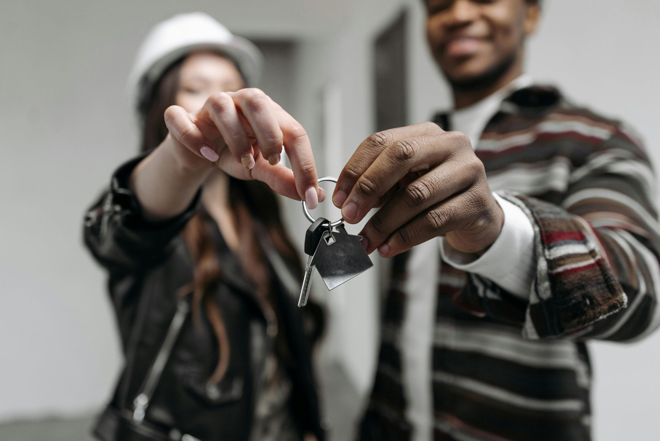 Two people wearing hard hats holding up a house key together.