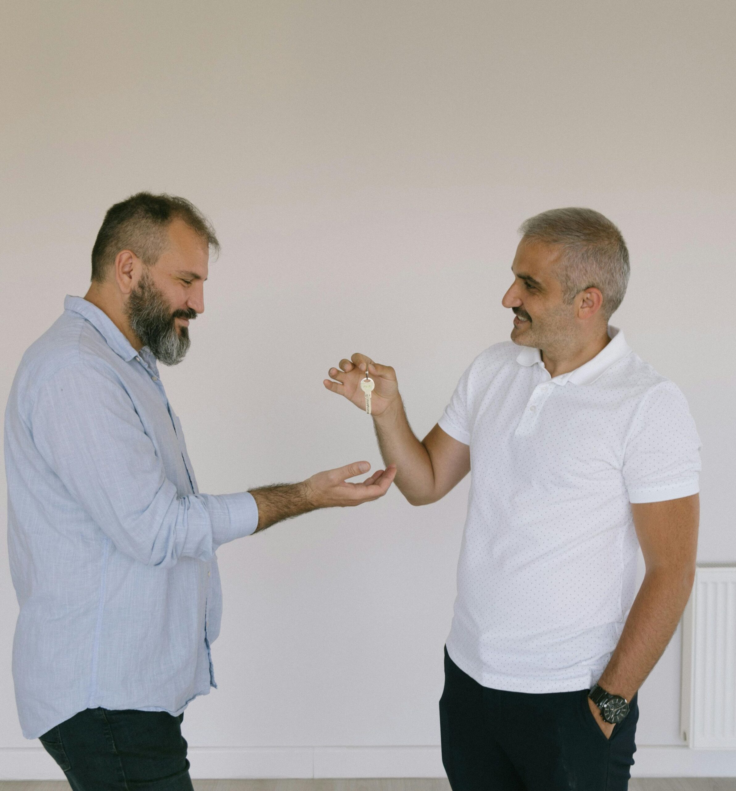 A broker handing a house key to a male housebuyer.