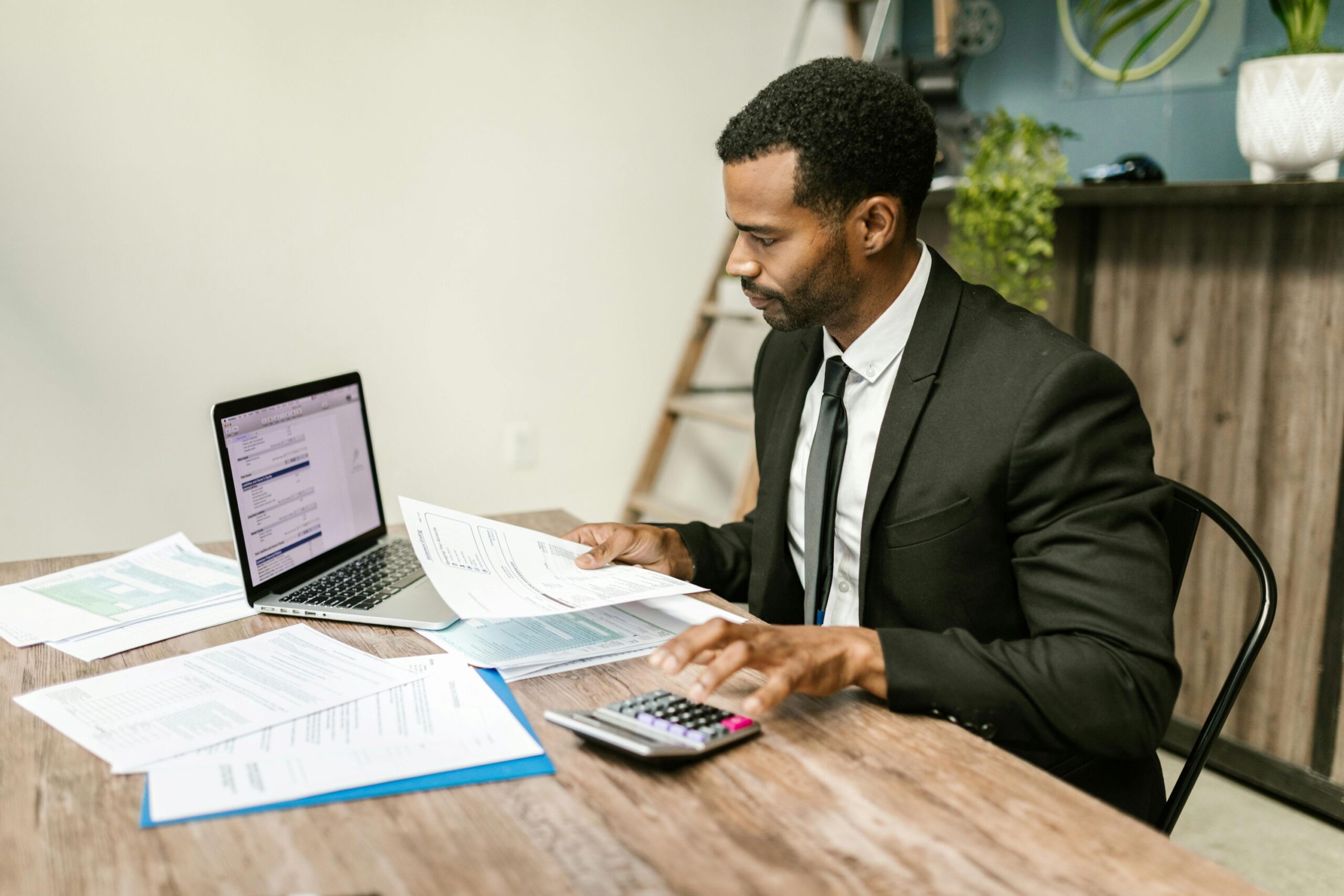 A male agent working on his desk, looking and calculating documents.