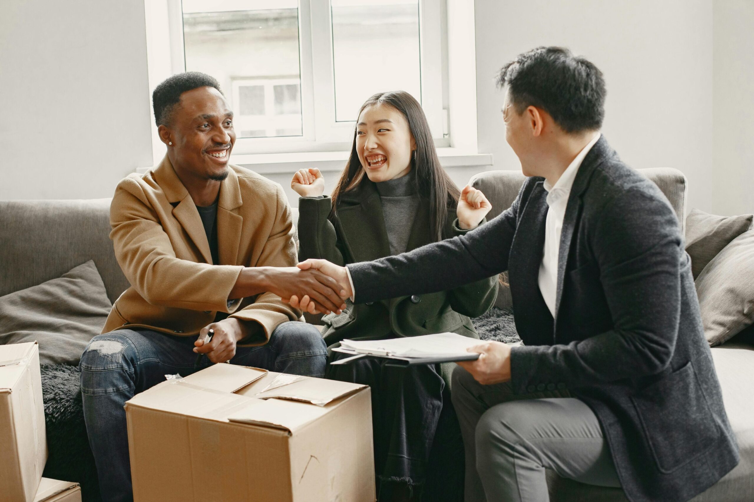 A happy couple on a couch talking with male broker.